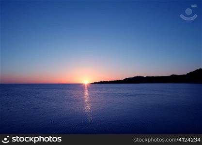 Beautiful sunset sunrise over blue sea ocean in red sky