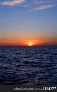 Beautiful sunset sunrise over blue sea ocean in red sky