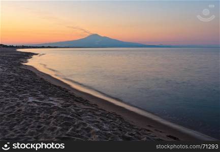 Beautiful sunset twilight on Agnone Bagni sea beach with smoky Etna volcano in far (Siracusa, Sicily, Italy)