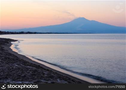 Beautiful sunset twilight on Agnone Bagni sea beach with smoky Etna volcano in far (Siracusa, Sicily, Italy)