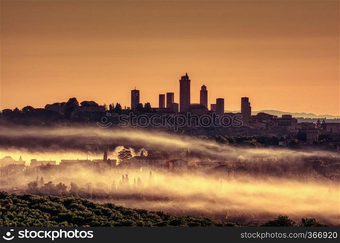 Beautiful sunset with fog at San Gimignano medieval village, Italy.