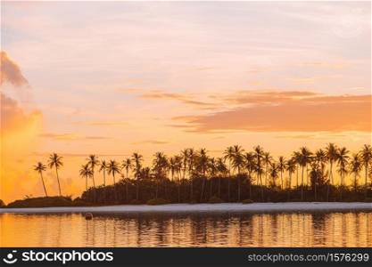 Beautiful sunset with palm trees silhouette and colorful sky on exotic island. Perfect white beach with turquoise water at ideal island