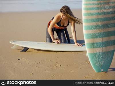 Beautiful surfer girl at the beach getting ready for surfing