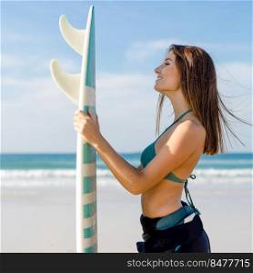 Beautiful surfer girl at the beach holding a surfboard 