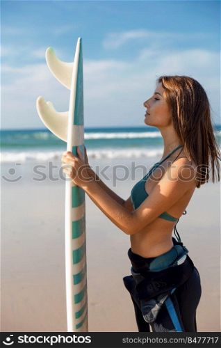 Beautiful surfer girl at the beach holding a surfboard 