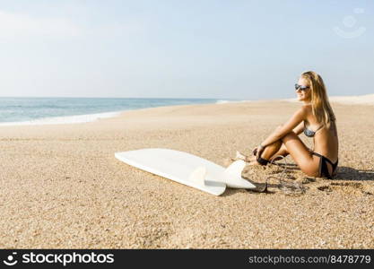 Beautiful surfer girl getting ready to surf and putting the leash