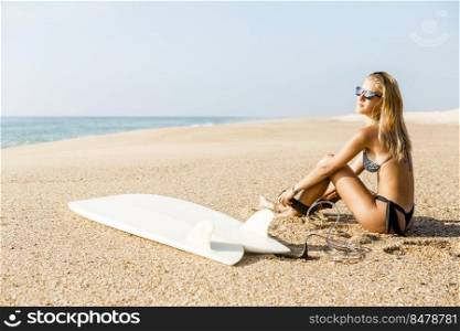 Beautiful surfer girl getting ready to surf and putting the leash