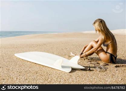 Beautiful surfer girl getting ready to surf and putting the leash