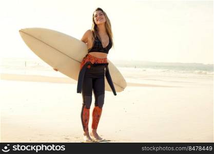 Beautiful surfer girl holding a surfboard and laughing