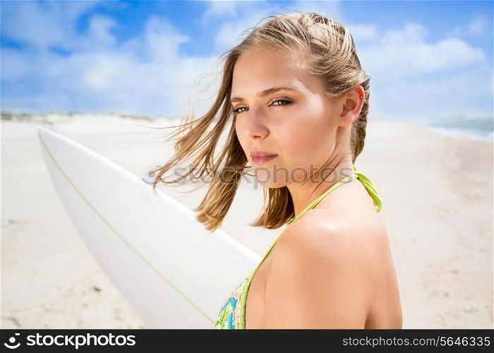 Beautiful surfer girl holding a surfboard on the beach