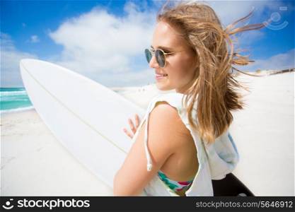 Beautiful surfer girl holding a surfboard on the beach