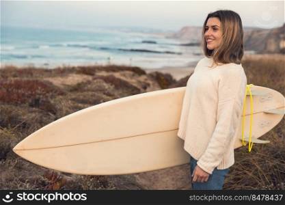 Beautiful surfer girl near the coastline with her surfboard searching for waves