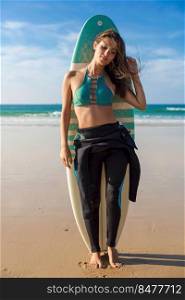 Beautiful surfer girl on the beach with her surfboard