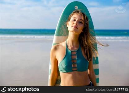 Beautiful surfer girl on the beach with her surfboard