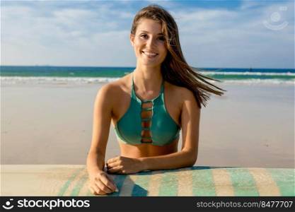 Beautiful surfer girl on the beach with her surfboard and smiling