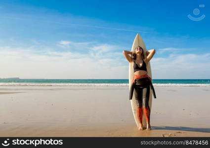 Beautiful surfer girl on the beach with her surfboard and smiling