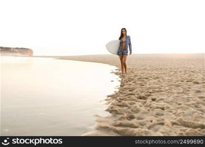 Beautiful surfer girl walking in the beach with her surfboard at sunset