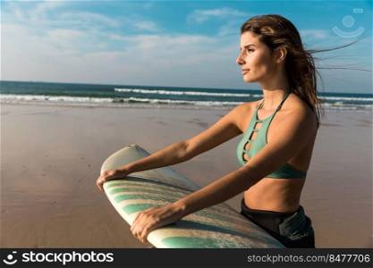 Beautiful surfer girl walking over the beach with her surfboard