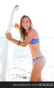 Beautiful surfer teen girl with surfboard on beach shore high key
