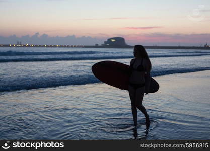 Beautiful surfer walking at the beach at sunset