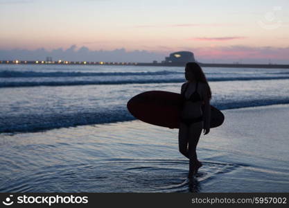 Beautiful surfer walking at the beach at sunset