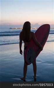 Beautiful surfer walking at the beach at sunset