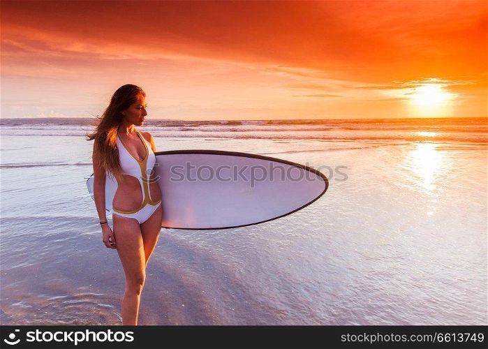 Beautiful surfer woman on the beach at sunset. Surfer woman on beach at sunset