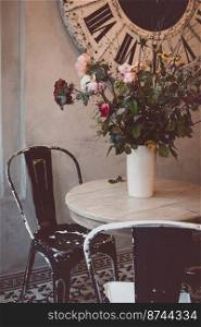 beautiful table and chairs in a cafe - a bouquet with roses in a vase 