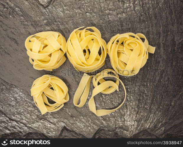 Beautiful Tagliatelle homemade Italian pasta from durum wheat on stone background, closeup.