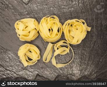 Beautiful Tagliatelle homemade Italian pasta from durum wheat on stone background, closeup.