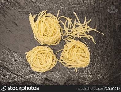Beautiful Tagliatelle homemade Italian pasta from durum wheat on stone background, closeup.