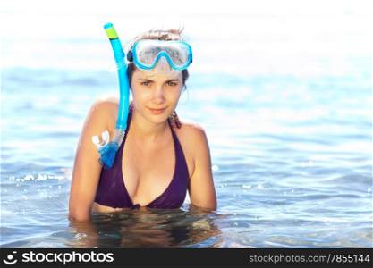 Beautiful tanned girl in snorkel gear chest-deep in water