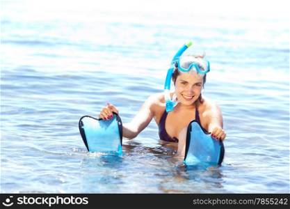 Beautiful tanned girl in snorkel gear sitting in water