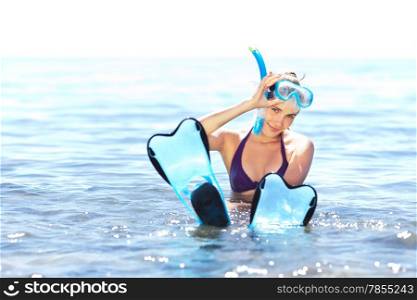 Beautiful tanned girl with snorkeling equipment resting in shallow water
