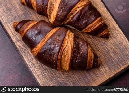 Beautiful tasty fresh crispy croissant on a dark concrete background. Dessert for a delicious nutritious breakfast