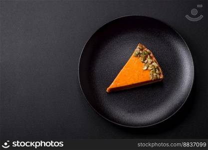 Beautiful tasty pumpkin pie with slices on a black ceramic plate on a dark concrete background