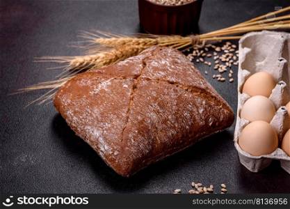 Beautiful tasty, square-shaped brown bread on a dark concrete background. Baking bread at home. Beautiful tasty, square-shaped brown bread on a dark concrete background