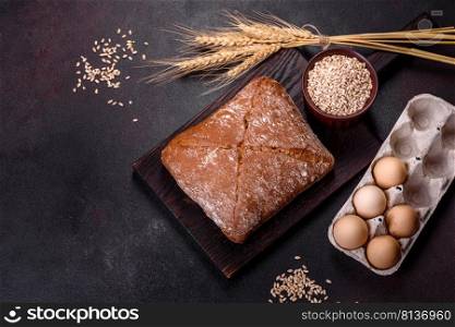 Beautiful tasty, square-shaped brown bread on a dark concrete background. Baking bread at home. Beautiful tasty, square-shaped brown bread on a dark concrete background