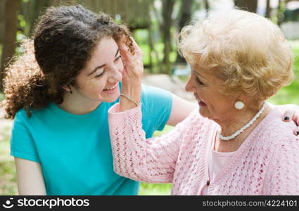 Beautiful teen girl and her loving grandmother smiling at eachother.