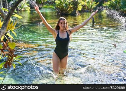 Beautiful teen girl in cenote of Riviera Maya splashing water with swimsuit