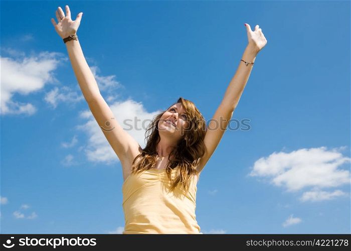 Beautiful teen girl raising her arms and looking to heaven in praise.