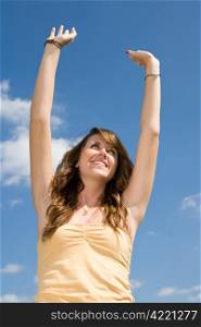 Beautiful teen girl raising her arms in praise or worship. Vertical view.