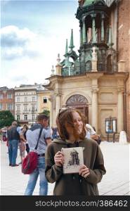 Beautiful teen girl sit and paint on the square. Wroclaw, Poland