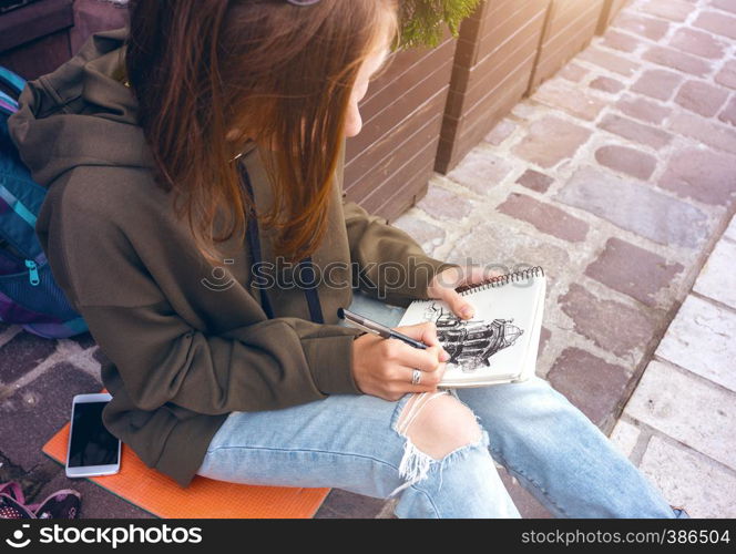 Beautiful teen girl sit and paint on the square. Wroclaw, Poland