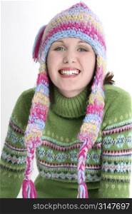 Beautiful teen girl with dazzling smile in green sweater and crazy winter hat.