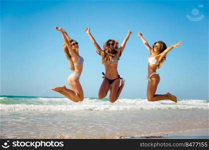 Beautiful teenage friends jumping on the beach