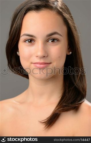 Beautiful teenage girl cosmetics skin care brunette portrait on gray