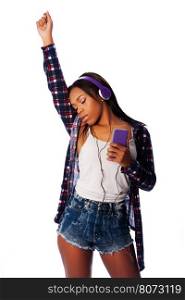 Beautiful teenager girl listening, dancing and jamming to music on mobile phone wearing purple headphones, on white.
