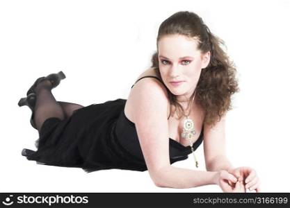 Beautiful teenager in black party dress lying on the floor