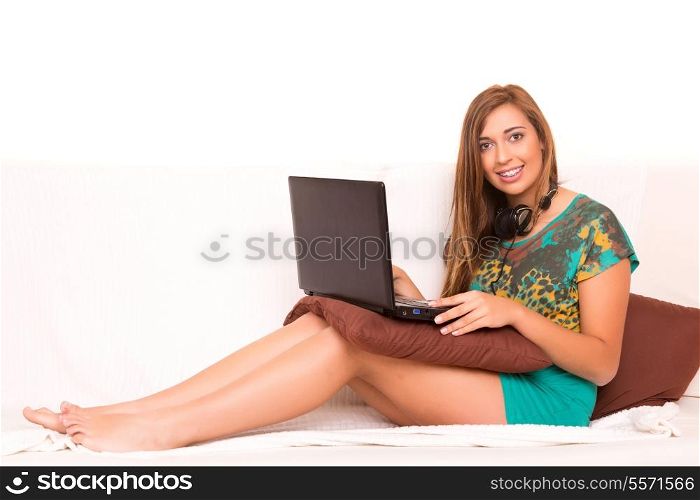 Beautiful teenager relaxing on the couch with the company of a last generation computer